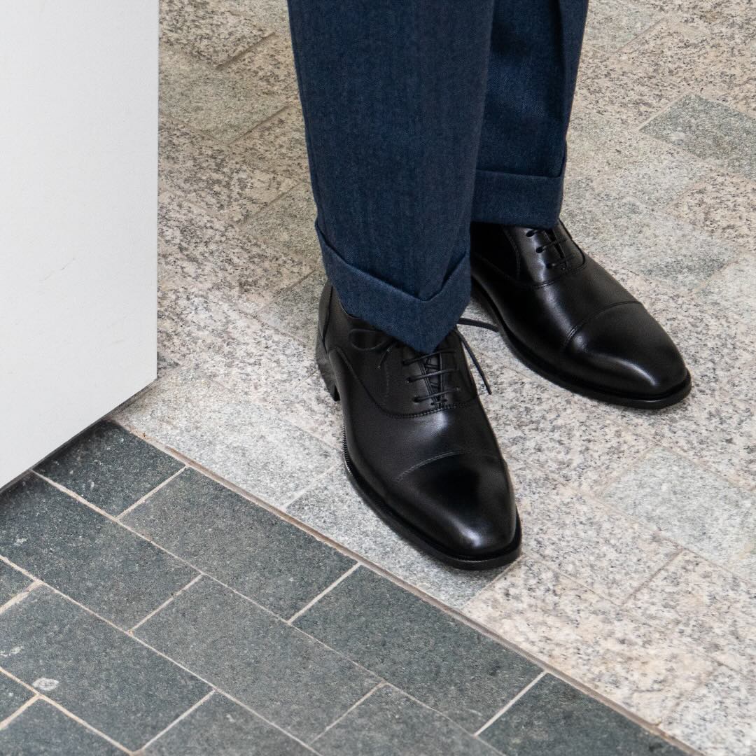 black oxford captoe paired with flannel blue trousers